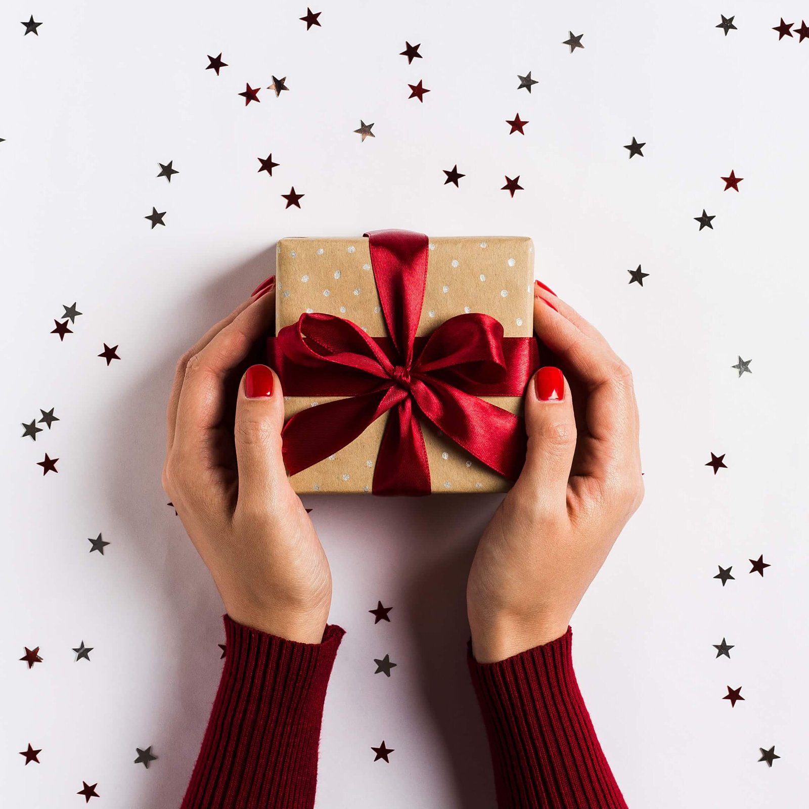 woman-hands-holding-christmas-holiday-gift-box-on-decorated-festive-table